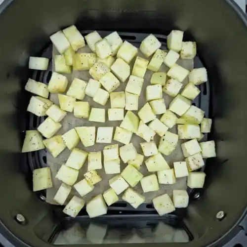  Peeled and chopped raw aubergine tossed in oil, salt and pepper. Placed in a baking paper lined air fryer basket ready for roasting. 