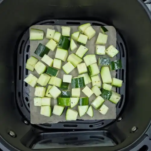  Chopped raw zucchini tossed in oil, salt and pepper. Placed in a baking paper lined air fryer basket ready for roasting. 