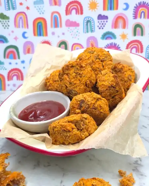  Crispy baked Veggie Nuggets served on a plate with a dipping bowl of tomato sauce. 